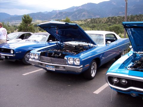 1972 Ford Ranchero - Three blue cars are parked in a lot with their hoods open; mountains are visible in the distance.