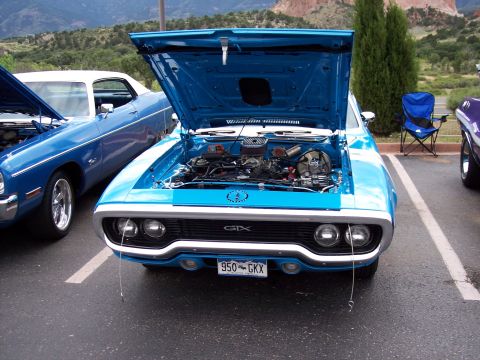 1972 Ford Ranchero - A blue 1971 Plymouth GTX is displayed with its hood open, parked in a lot with other vehicles.
