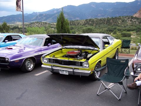 1972 Ford Ranchero - Two classic Mopar muscle cars are parked side-by-side with hoods up, their engines against a scenic mountain backdrop.