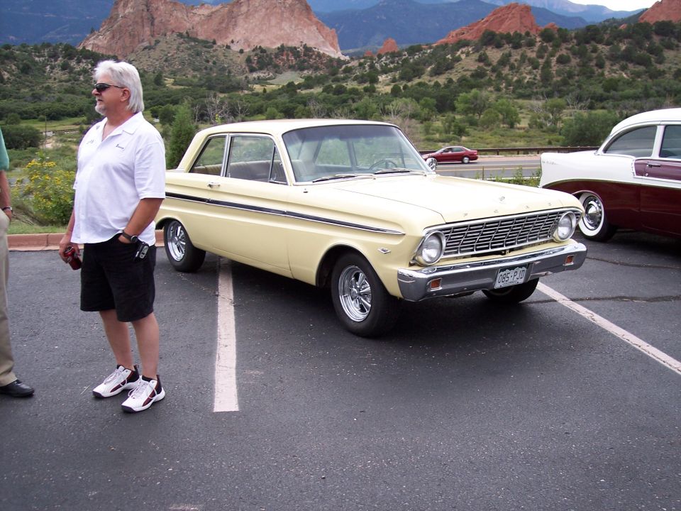 Yellow 1964 Ford Falcon sedan parked outdoors with a man beside it