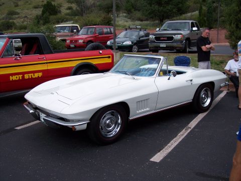1972 Ford Ranchero - A white convertible is parked in a lot with other vehicles, including a red truck with yellow stripes.