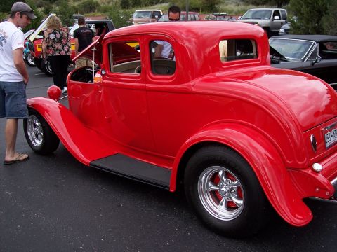 1972 Ford Ranchero - A bright red 1932 Ford coupe hot rod is displayed at a car show, with people milling around.