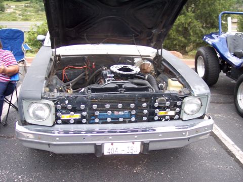 1972 Ford Ranchero - Front view of a 1975 Chevrolet Nova with hood open, revealing the engine and custom grille. A blue dune buggy is parked nearby.