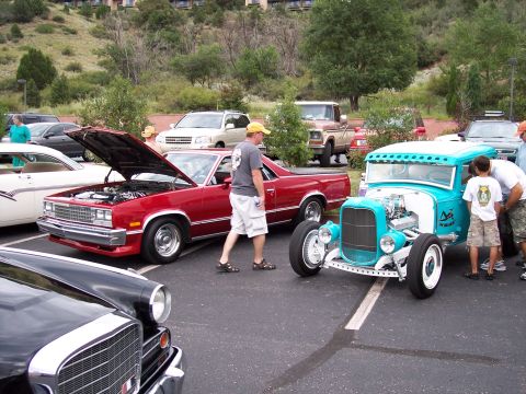 1972 Ford Ranchero - Several vehicles are parked in a lot, including a bright turquoise hot rod and a red El Camino with its hood open.