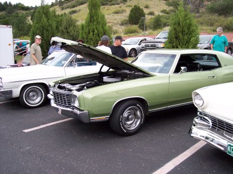 1972 Ford Ranchero - Three classic cars are parked at an outdoor event, with one having its hood open.