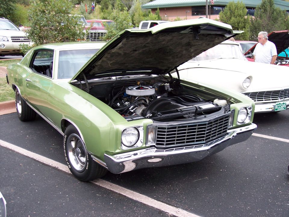 Green 1970 Monte Carlo with hood open, showing engine. Another car is parked next to it