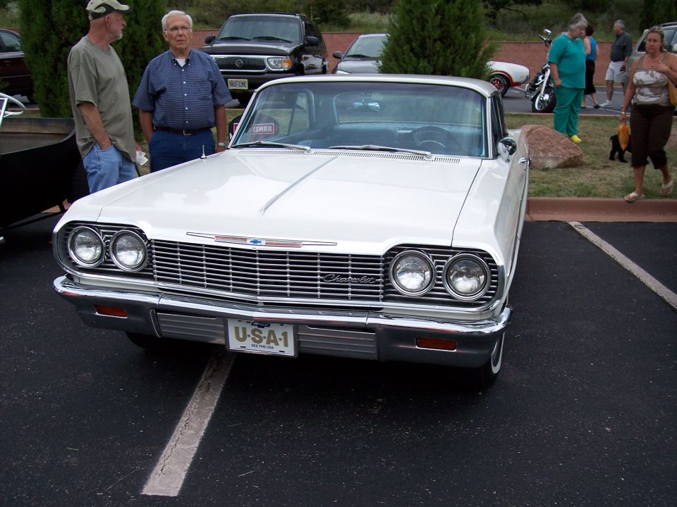 White Chevrolet sedan front view, chrome grille, dual headlights, USA-1 license plate