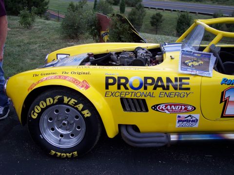 1972 Ford Ranchero - A yellow race car is parked outdoors with its hood open, revealing the engine.