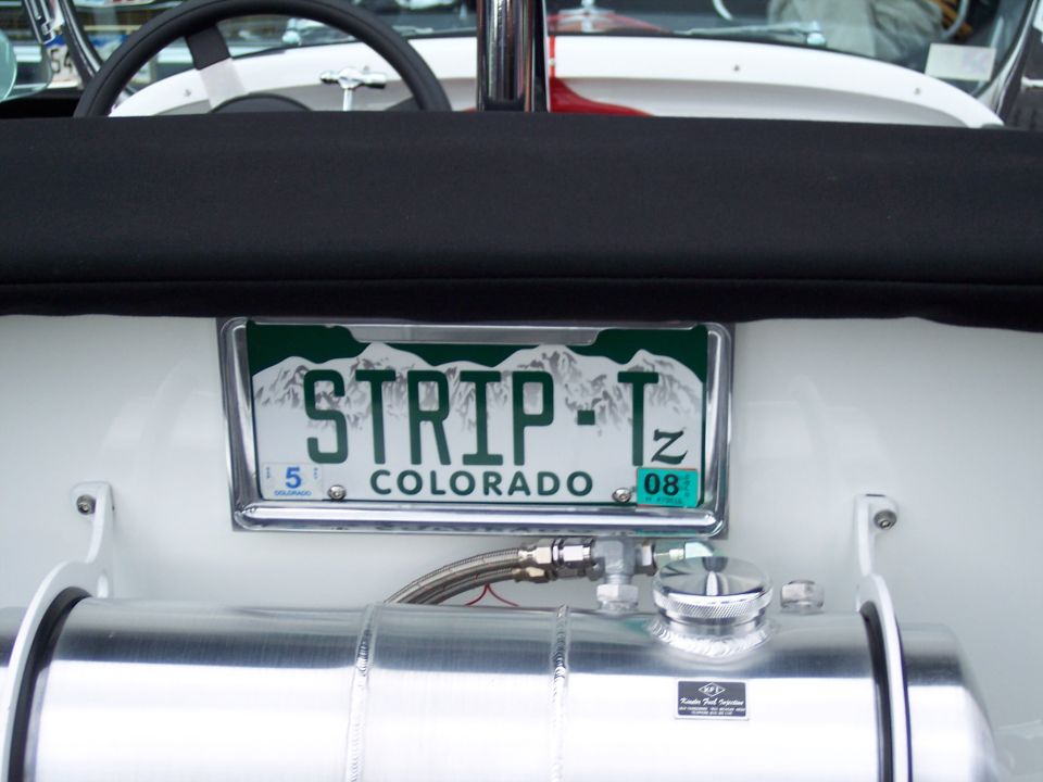 Colorado license plate reading STRIP-T mounted above a shiny metal tank in a vehicle's interior