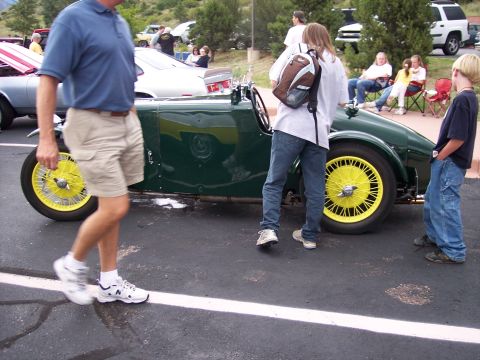 1972 Ford Ranchero - A vintage green sports car with bright yellow wire wheels is displayed outdoors with spectators.