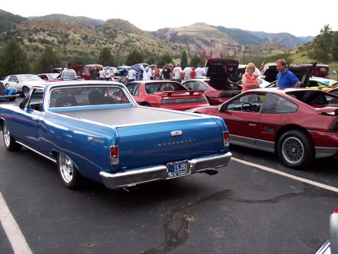 1972 Ford Ranchero - A blue El Camino is parked at a car show with other vehicles and mountains in the background.