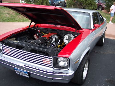 1972 Ford Ranchero - This two-tone red and silver vehicle displays its engine with the hood open, a prominent chrome grille and a license plate reading 053 HYD.