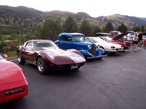 1972 Ford Ranchero - A maroon 1972 Chevrolet Corvette C3 is parked in a line of vehicles at a car show with mountains in the background.