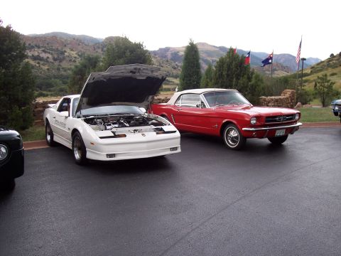 1972 Ford Ranchero - A white Pontiac Firebird and a red Ford Mustang convertible are parked outdoors with mountains in the background.