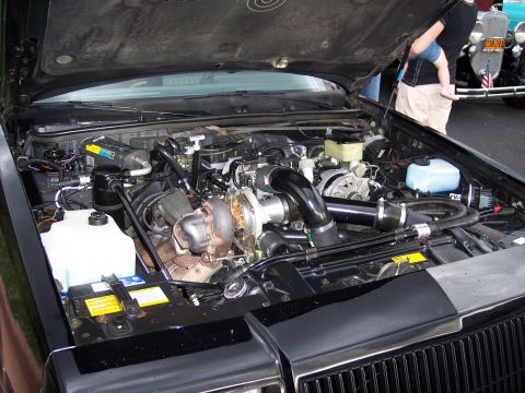 1972 Ford Ranchero - Customized engine bay a prominent turbocharger and intercooler setup, with other vehicles visible in the background.