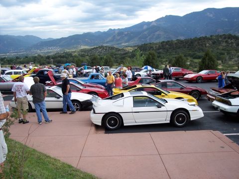 1972 Ford Ranchero - A gathering of cars is parked with a scenic mountain range under a cloudy sky.