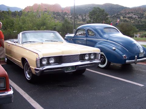 1972 Ford Ranchero - A tan 1967 Mercury Monterey convertible is parked next to a blue coupe, with mountains in the background.