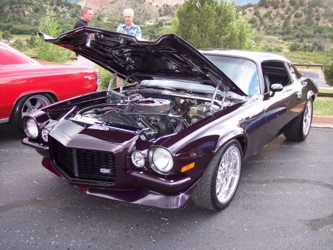 1972 Ford Ranchero - A dark purple coupe, likely from the early 1970s, is displayed with its hood open, revealing the engine bay and custom wheels.