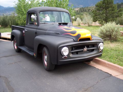 1972 Ford Ranchero - A matte black International Harvester pickup truck with custom flame decals on the hood is parked outdoors.