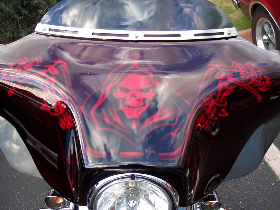 Motorcycle fairing with red grim reaper skull airbrushed on it. Another car is visible to the right