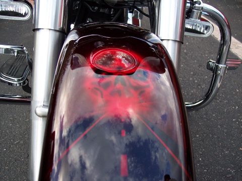 1972 Ford Ranchero - A motorcycle's front fender displays custom red flame artwork and reflects the sky.