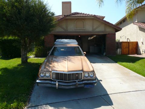1975 Ford Ranchero - A 1975 Ford Ranchero, identified by its distinctive body style, is parked in front of a suburban garage, topped with a camper shell.