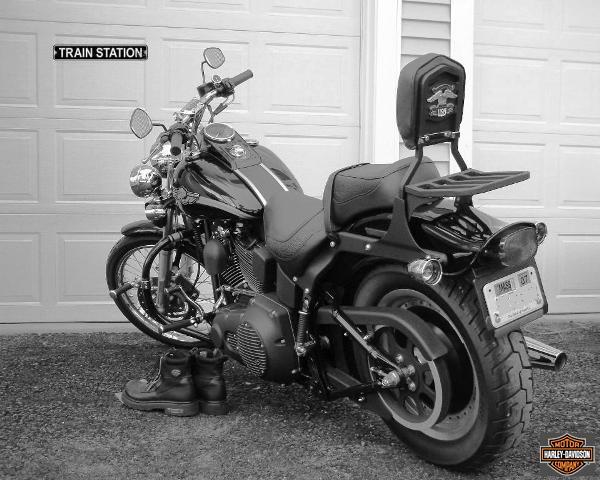 Blacked-out Harley-Davidson Softail with sissy bar and luggage rack, 3/4 rear view in B&W