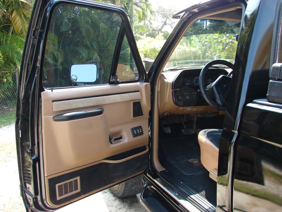Black 1987 Ford F-150 interior with tan door panel and seats, viewed from driver's side