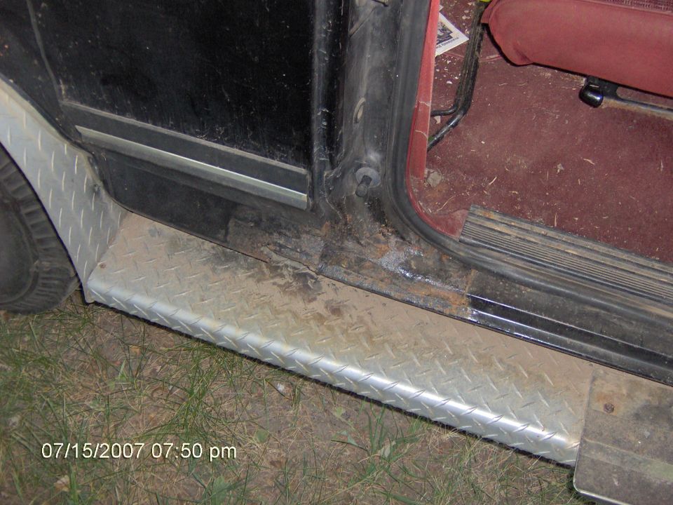 Black SUV rocker with diamond-plate guard, rusty door sill and red interior carpet