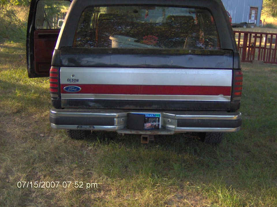 Rear of black Ford Bronco with red and silver tailgate stripe, Ford oval and hitch