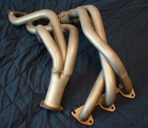 1992 Ford Probe - A pair of silver exhaust headers are laid out on a dark blue quilted fabric background.