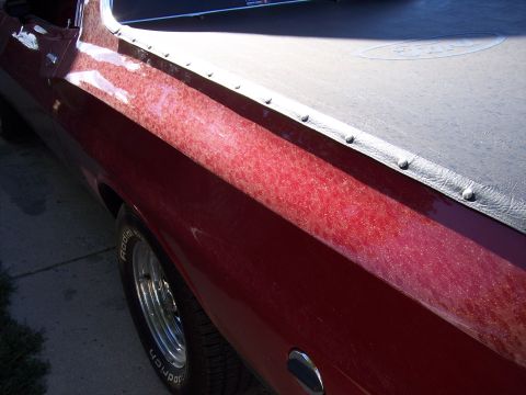 1972 Ford Ranchero - Side view of a red 1972 Ford Ranchero pickup truck, showing the bed cover and rear fender.