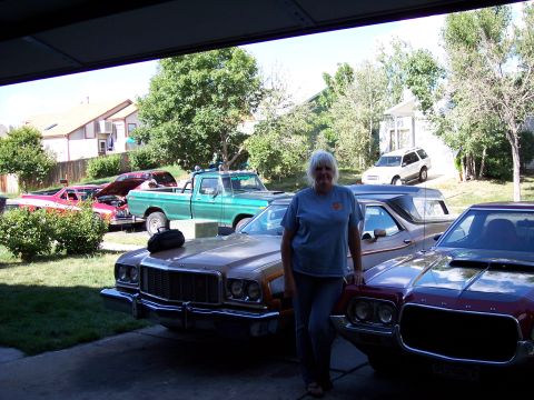 1972 Ford Ranchero - A woman stands in a garage next to a brown 1972 Ford Ranchero, with other vehicles visible in the background.