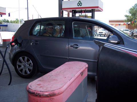 1972 Ford Ranchero - A gray Volkswagen Golf is being refueled at a gas station with two passengers inside.