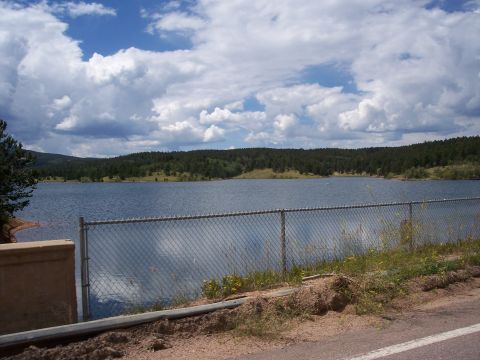 1972 Ford Ranchero - A wide shot of a lake surrounded by trees under a cloudy sky, with a fence in the foreground.