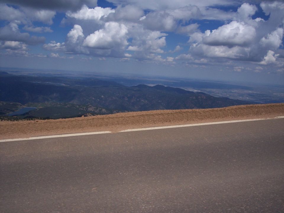Mountain landscape with a paved road in the foreground and distant hills under a cloudy sky