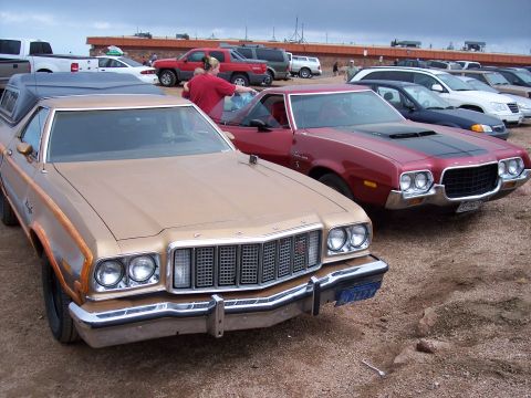 1972 Ford Ranchero - Two Ford Rancheros are parked in a lot with other vehicles under a cloudy sky.