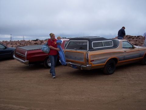 1972 Ford Ranchero - A woman carries a child past a 1972 Ford Ranchero with a camper shell and distinctive two-tone paint.