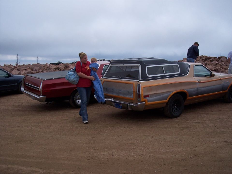 1972 Ford Ranchero with a camper shell, tan and gray two-tone paint, and wood-grain trim, viewed from the rear three-quarter angle