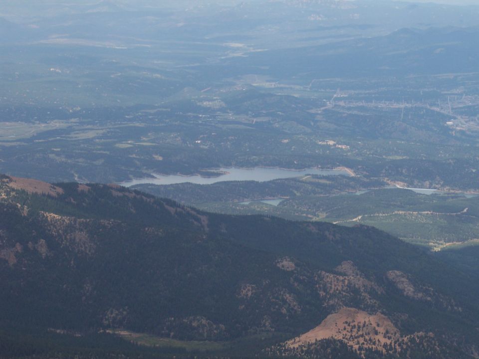 Aerial view of a mountain landscape with a lake and distant town