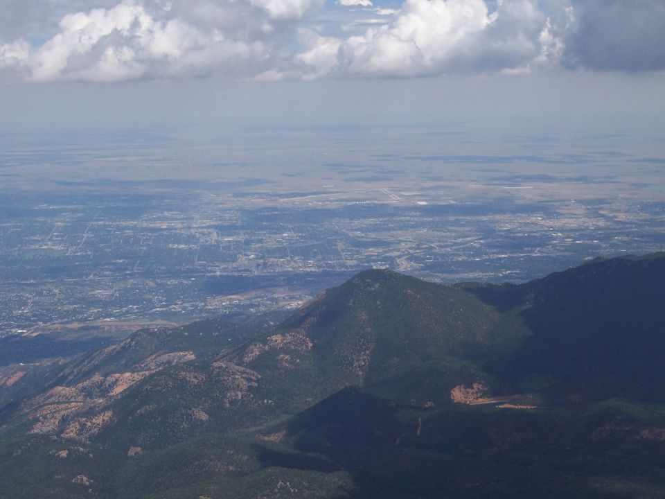 Mountainous terrain overlooking a city under a cloudy sky