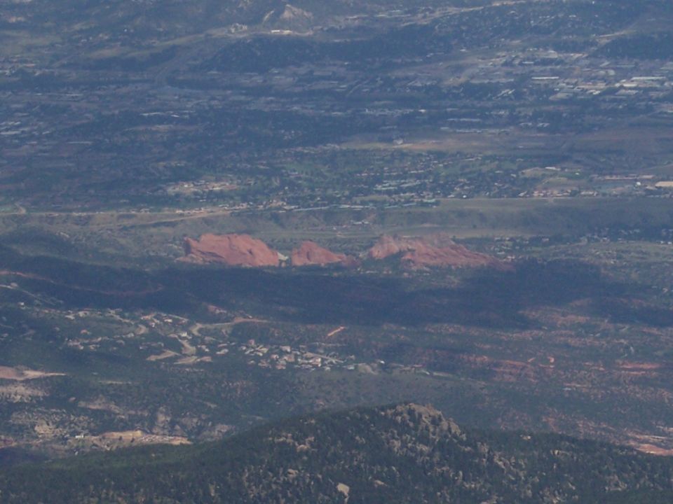 Red rock formations in a valley with distant mountains and scattered buildings