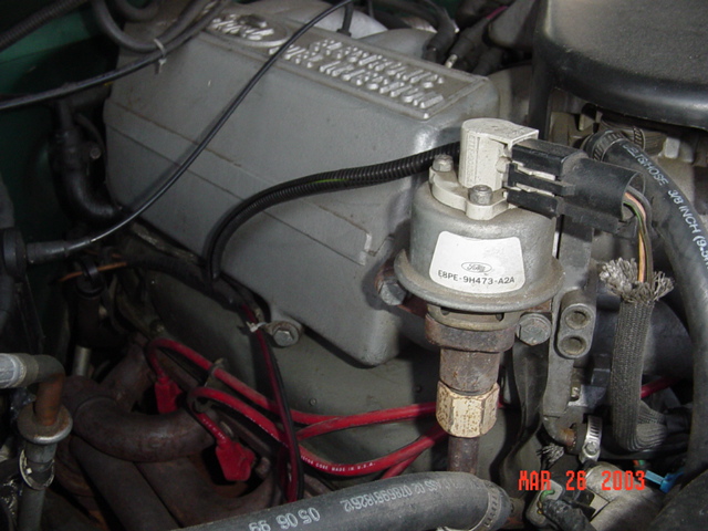 Close-up of a Ford EEC module and a temperature sensor with a brass fitting in an engine bay