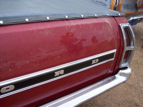 1972 Ford Ranchero - The rear of a red Ford pickup truck bed is visible, showing the 'FORD' badging and chrome bumper.