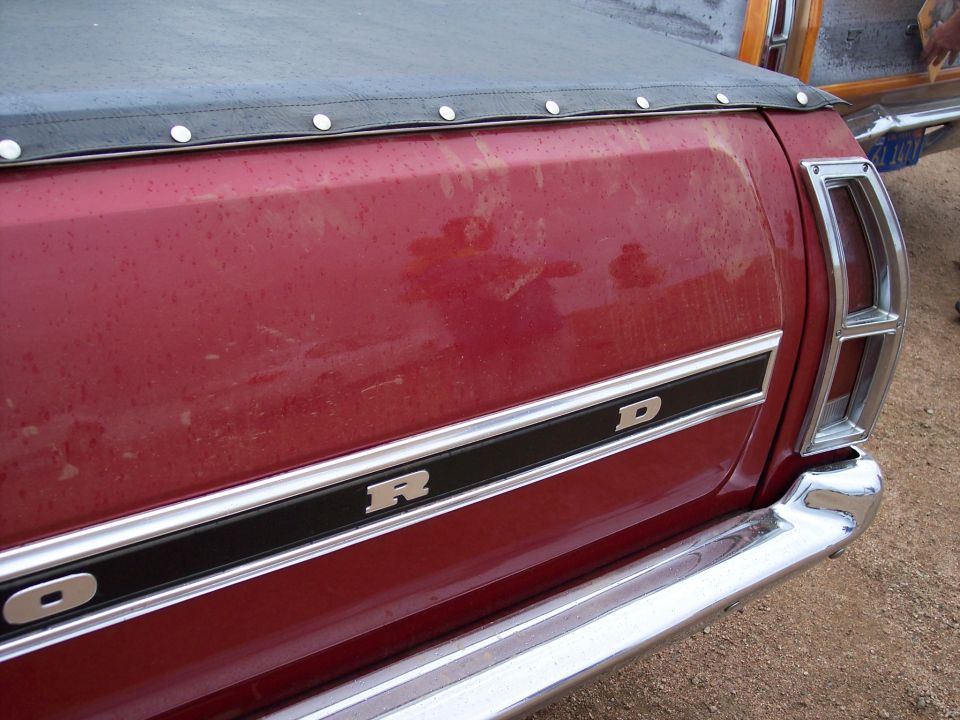 Red pickup truck bed with chrome trim spelling 'FORD' and a chrome bumper