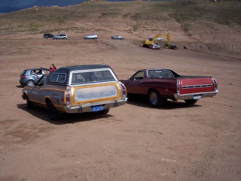 1972 Ford Ranchero - Two Ford Rancheros are parked on a dirt road, with other vehicles and construction equipment visible in the distance.