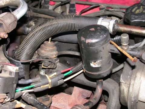 1987 Lincoln Town Car - This image shows a section of an engine bay with various hoses, wires, and a black cylindrical component.