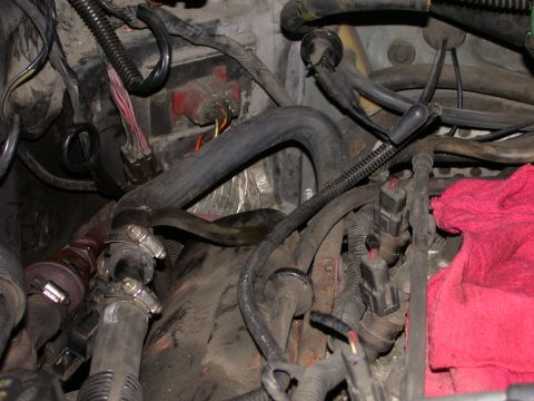 1987 Lincoln Town Car - Close-up view of a cluttered engine bay, showing hoses, wires, and connectors. No specific vehicle year is identifiable.