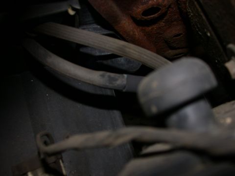 1987 Lincoln Town Car - Close-up view of engine hoses and a rusty metal bracket, likely related to vacuum leaks.