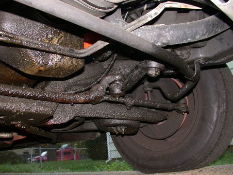 1987 Lincoln Town Car - The underside of the vehicle is heavily coated in oil, obscuring many of the mechanical components.